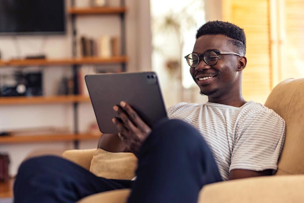 Adults - smiling man reading on a tablet at home