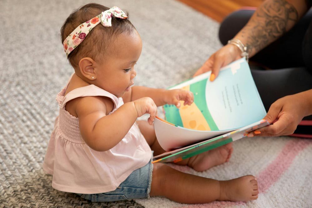 Young Children - baby with a headband looking at a children's book