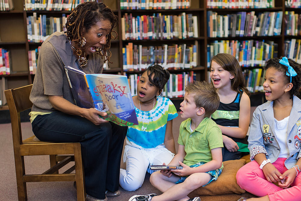 Kids storytime events at the library - children on the floor with librarian reading a book