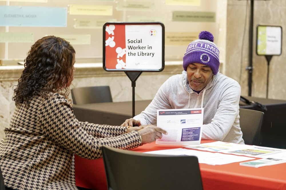 social workers in the Pratt Library helping a man at a table