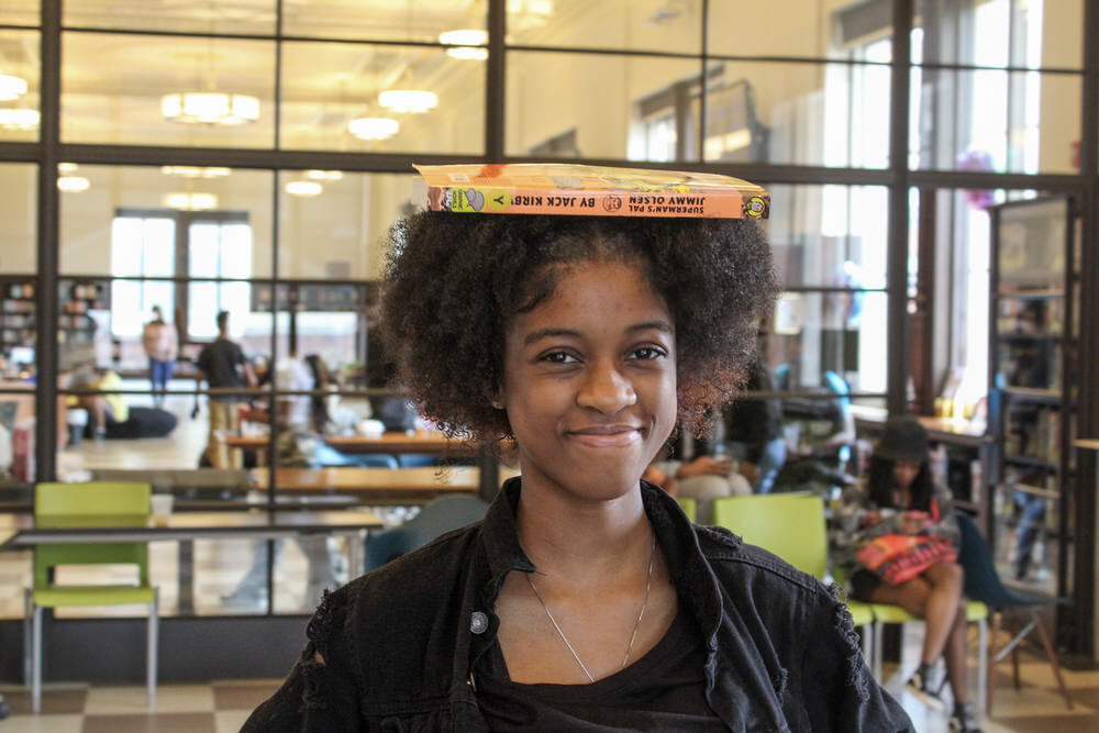 a student in the Teen Center smiling while balancing a book on their head