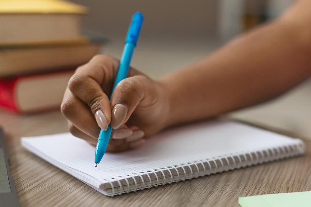 writing hand with pen to notebook