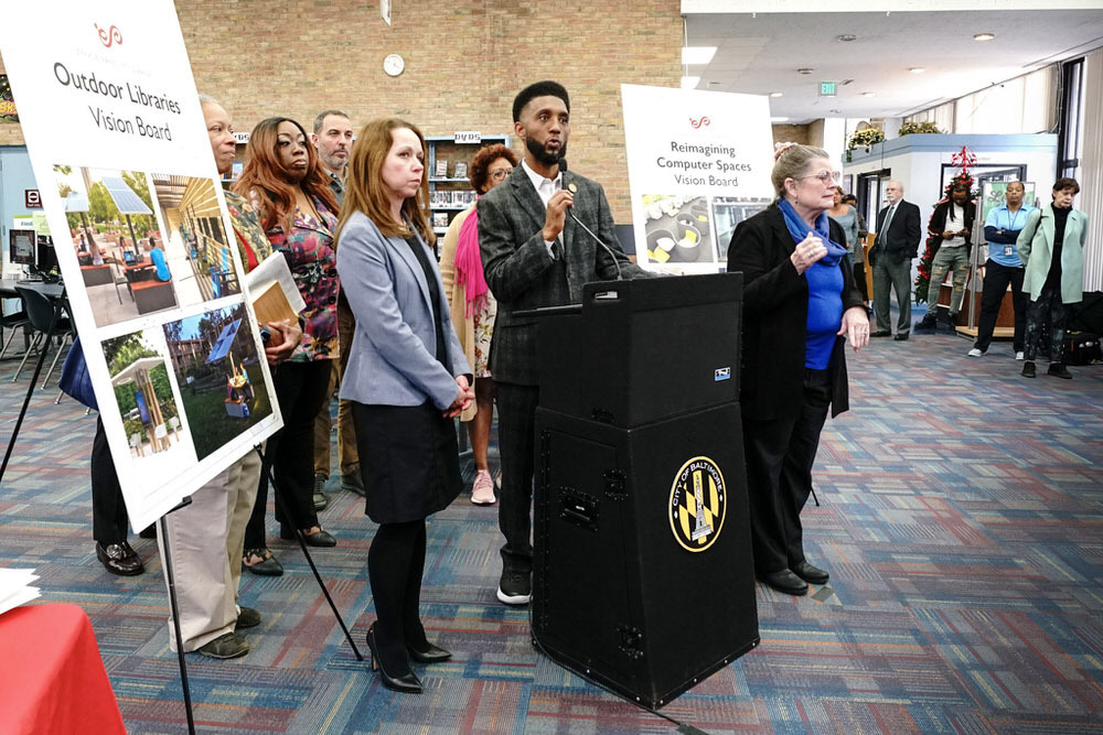 Baltimore Mayor Brandon M. Scott at a Pratt Library event in 2021 with signs promoting library improvements