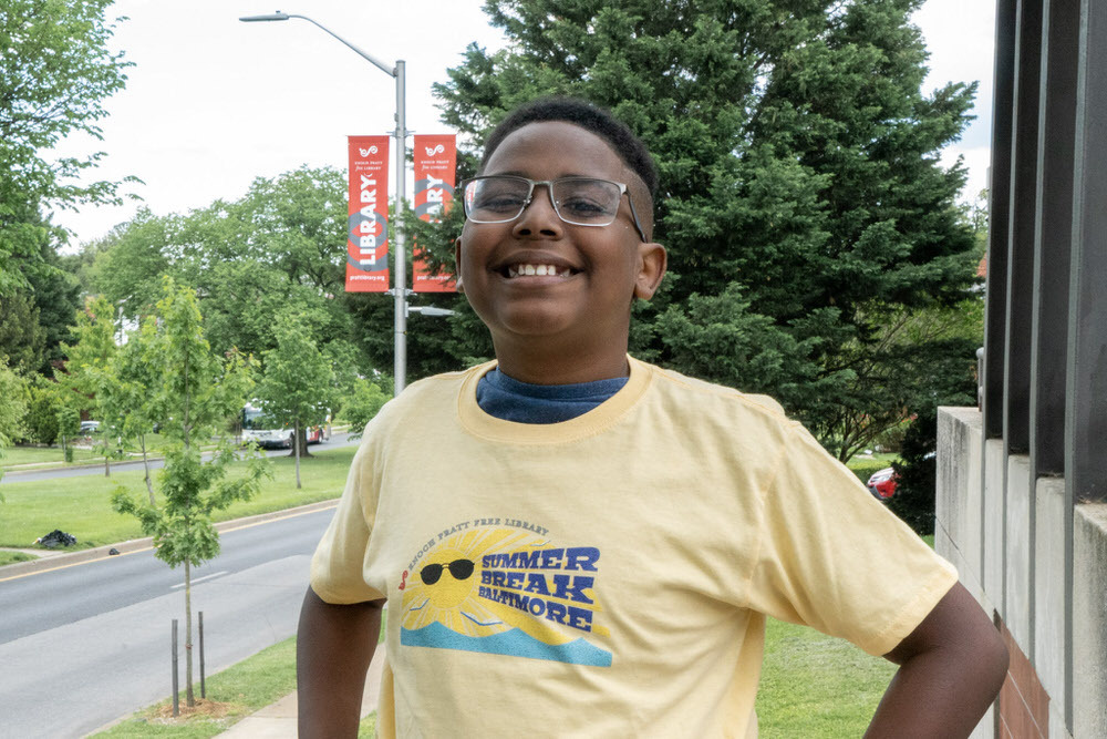 Summer Break Baltimore - smiling child wearing the 2021 shirt