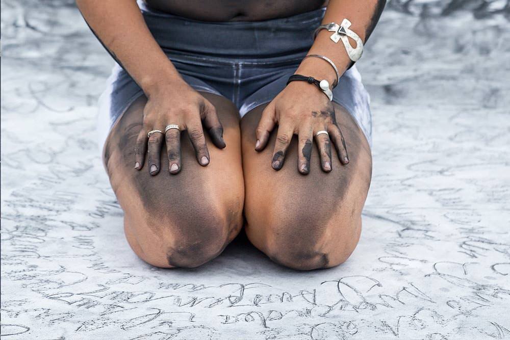 Phylicia Ghee art detail - kneeling artist surrounded by written words