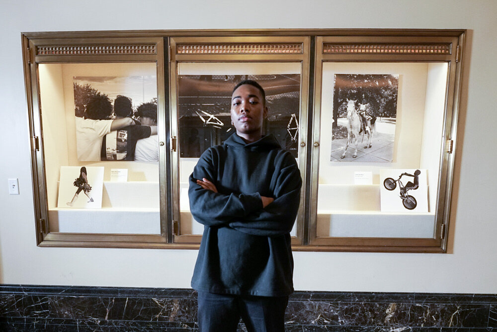 SHAN Wallace, Artist in Residence at Pratt Library posing by her photo exhibit