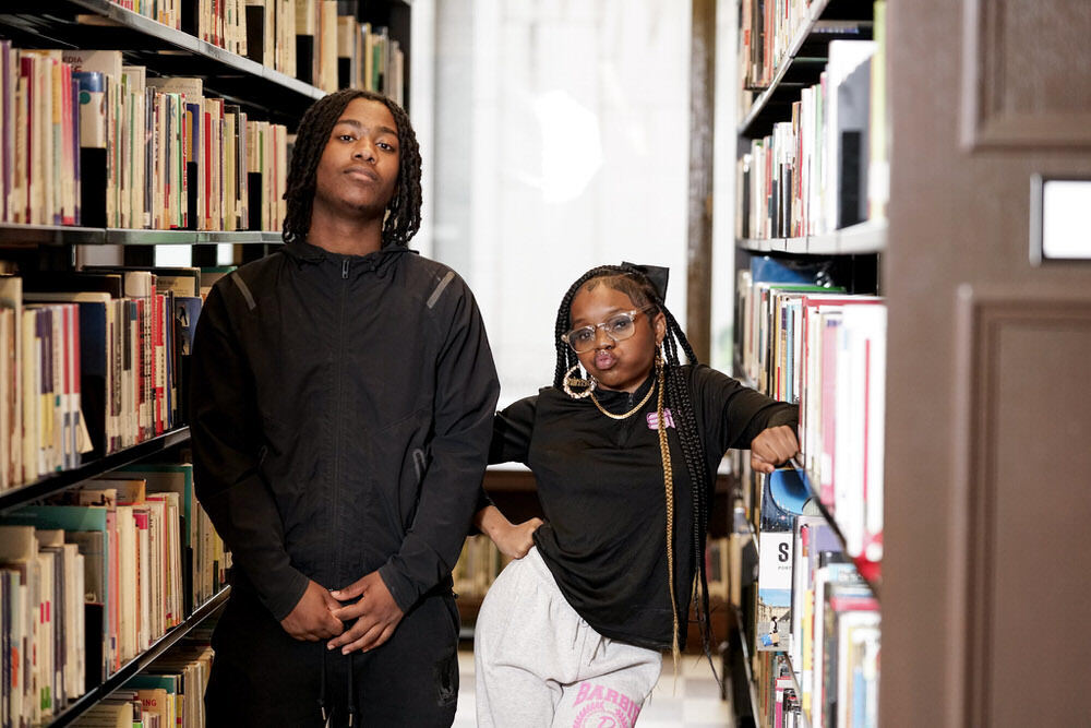 two teen Prattpreneurs posing between bookshelves