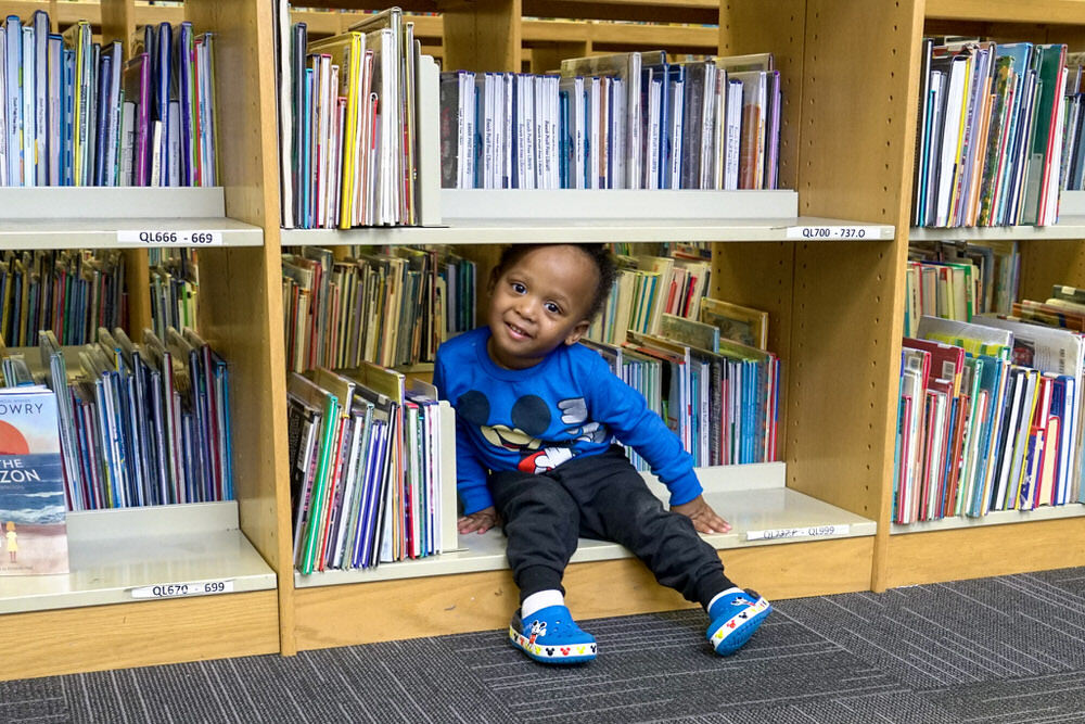 smiling young boy in bookshelves